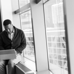 Grayscale Photo of Man Using Laptop