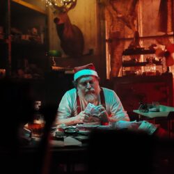 Man in Santa Hat Sitting on Chair Counting Money