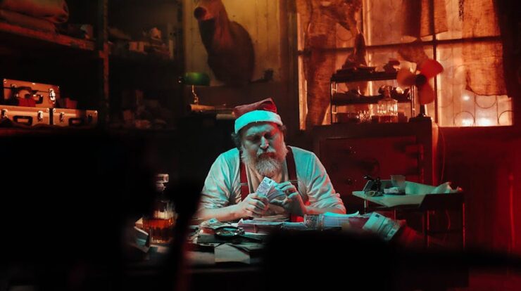 Man in Santa Hat Sitting on Chair Counting Money