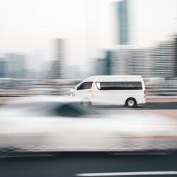 a white van driving down a street next to tall buildings