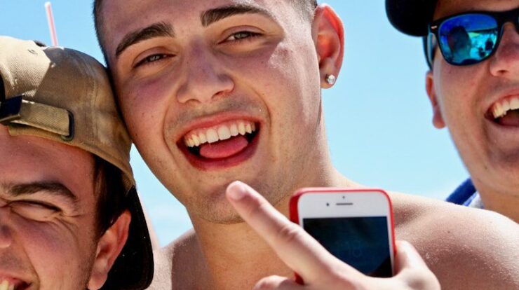 man holding iPhone in between two men