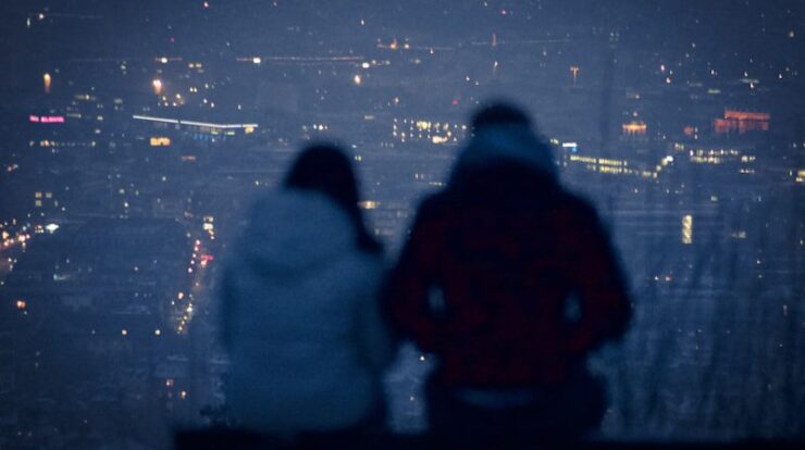 man and woman sitting on bench during night time