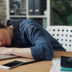 a woman laying her head on a laptop