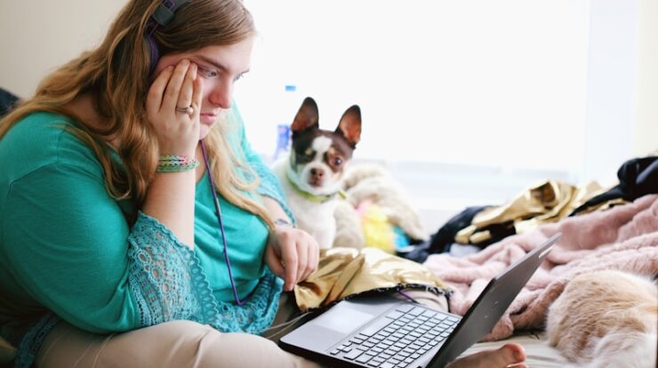 woman in teal long sleeve shirt holding black laptop computer