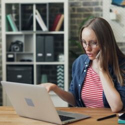 a woman sitting at a table using a laptop computer